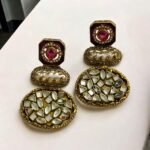 Vintage-style gold earrings with blue and pearl accents, featuring geometric-shaped stones.