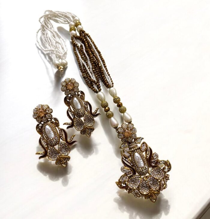 Elegant black gemstone and pearl necklace set with gold-tone accents, including matching earrings with a floral design.