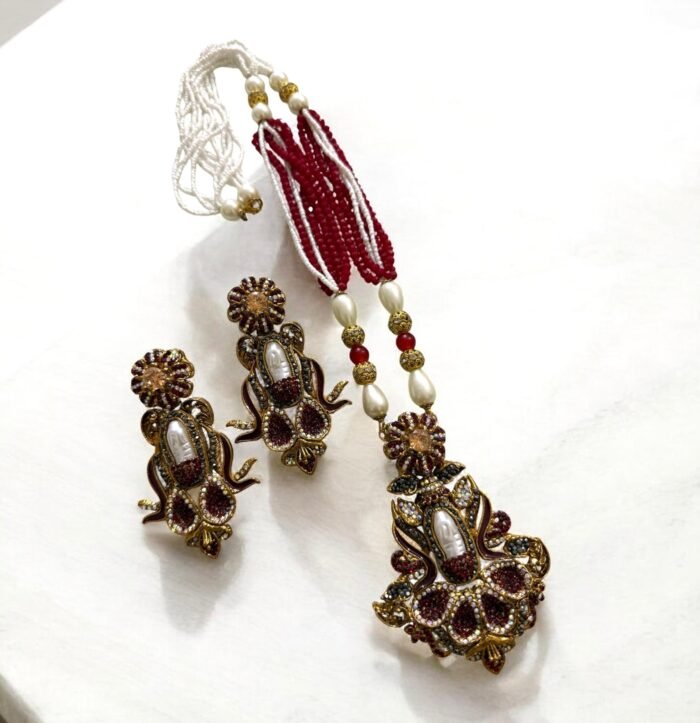 Elegant black gemstone and pearl necklace set with gold-tone accents, including matching earrings with a floral design.