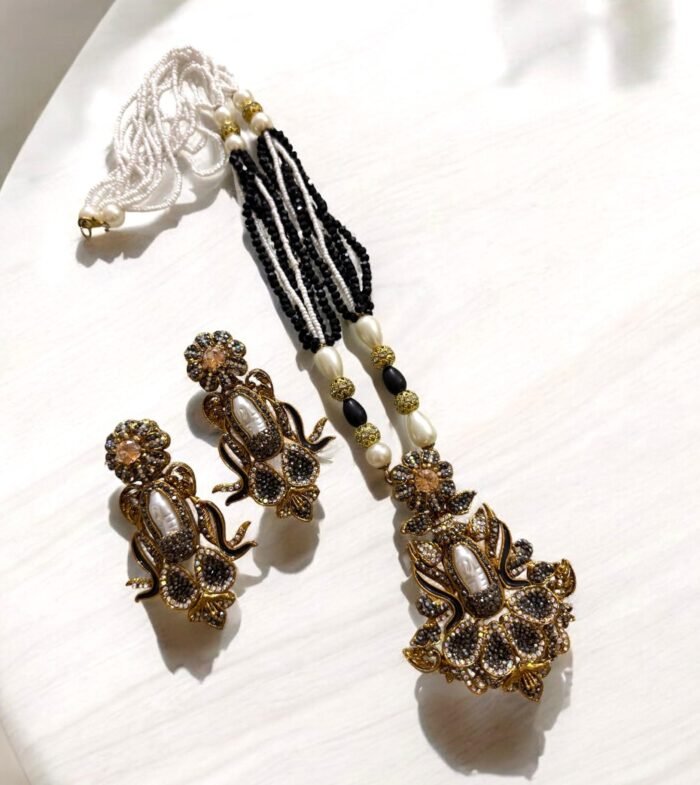Elegant black gemstone and pearl necklace set with gold-tone accents, including matching earrings with a floral design.