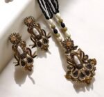 Elegant black gemstone and pearl necklace set with gold-tone accents, including matching earrings with a floral design.