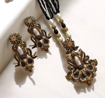 Elegant black gemstone and pearl necklace set with gold-tone accents, including matching earrings with a floral design.