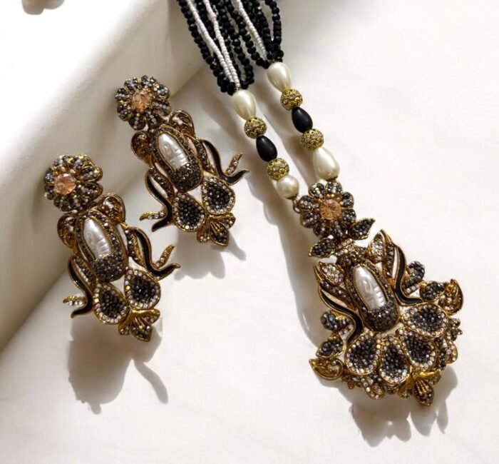 Elegant black gemstone and pearl necklace set with gold-tone accents, including matching earrings with a floral design.