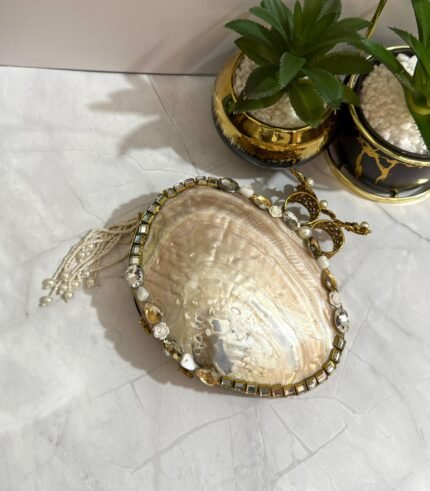 White and gold evening clutch with crystal and pearl embellishments, featuring a bird-shaped handle and a pearl tassel.
