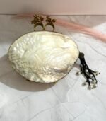 Black and gold vintage evening clutch with pearls, crystals, and a bird-shaped top handle, accompanied by a pearl tassel.
