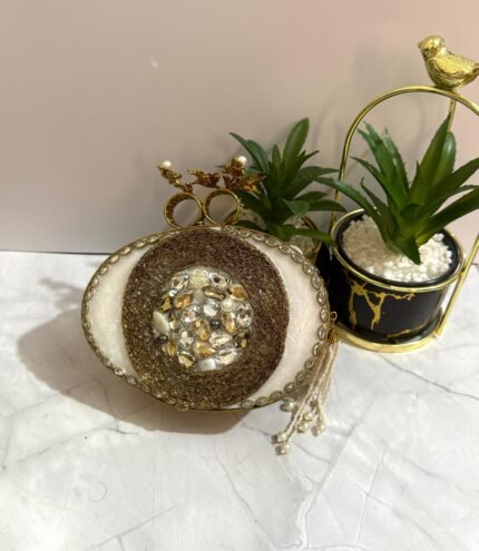 White and gold evening clutch with crystal and pearl embellishments, featuring a bird-shaped handle and a pearl tassel.