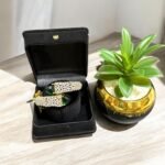 Gold bracelet with green stones and sparkling crystal embellishments.