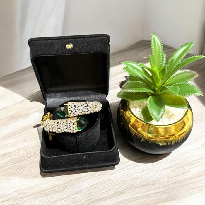 Gold bracelet with green stones and sparkling crystal embellishments.