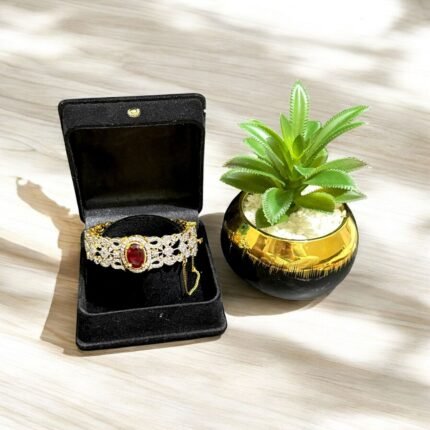 Gold bracelet with a ruby center stone and crystal accents.