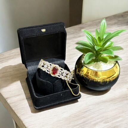 Gold bracelet with a ruby center stone and crystal accents.