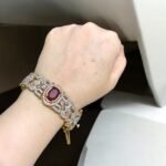 Gold bracelet with a ruby center stone and crystal accents.