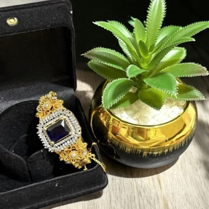 Gold bracelet with a sapphire stone centerpiece and crystal embellishments.
