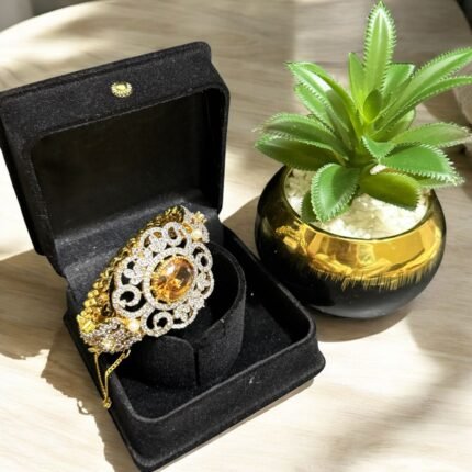 Gold bracelet with citrine center stone, crystal embellishments, and pearl accents.