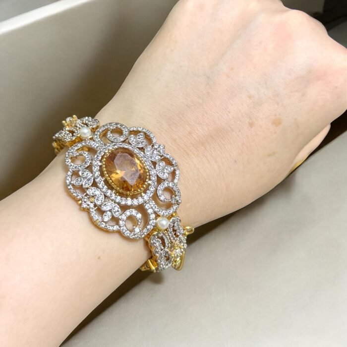 Gold bracelet with citrine center stone, crystal embellishments, and pearl accents.