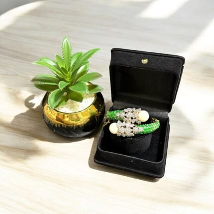 Gold bracelet with green stones, white pearls, and crystal embellishments.