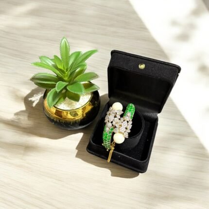 Gold bracelet with green stones, white pearls, and crystal embellishments.