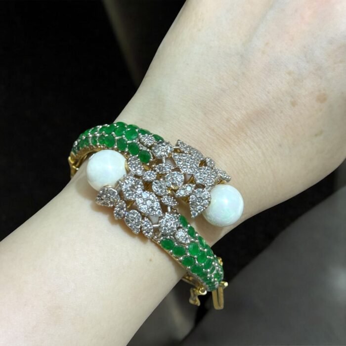 Gold bracelet with green stones, white pearls, and crystal embellishments.
