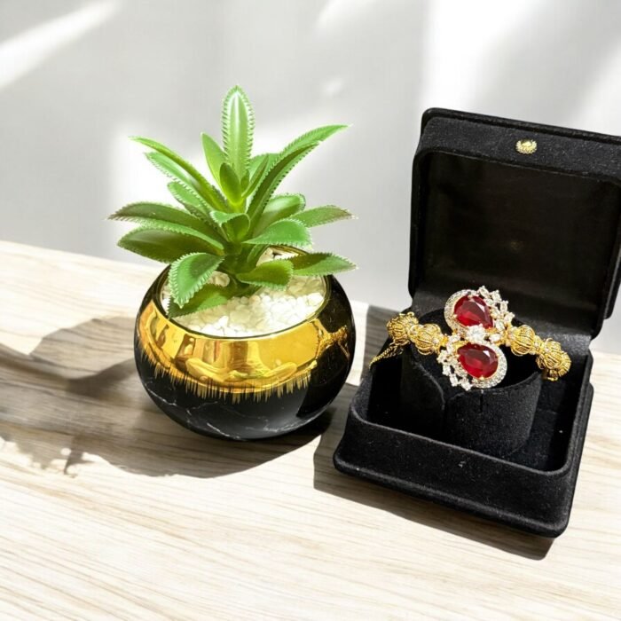 Gold bracelet with red teardrop stones and crystal embellishments.