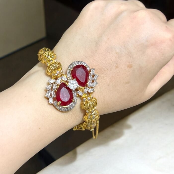 Gold bracelet with red teardrop stones and crystal embellishments.