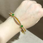 Gold bracelet with green stones and sparkling crystal accents.