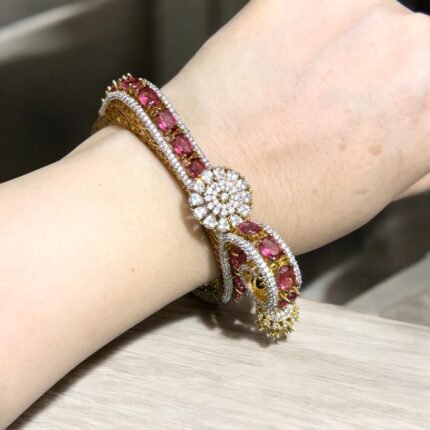 Gold bracelet with pink stones, crystals, and intricate gold detailing.