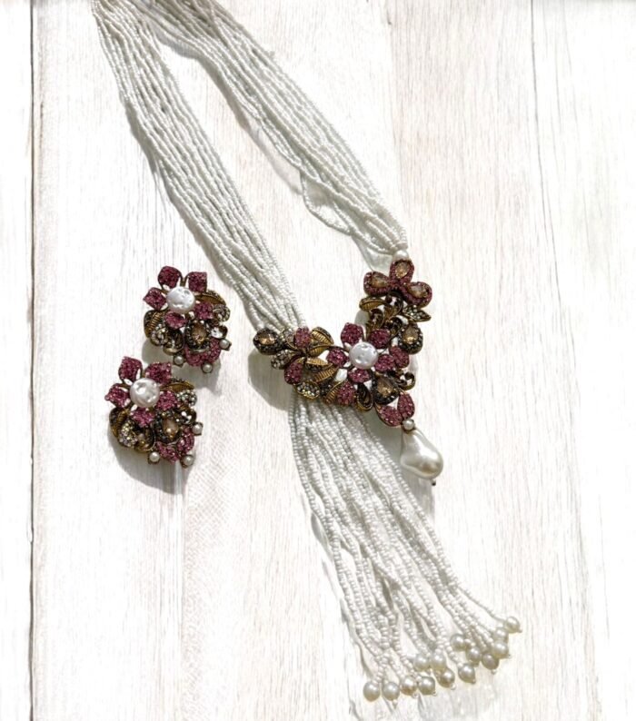 Gold-plated necklace with pink crystals, pearls, and floral accents, paired with matching earrings.