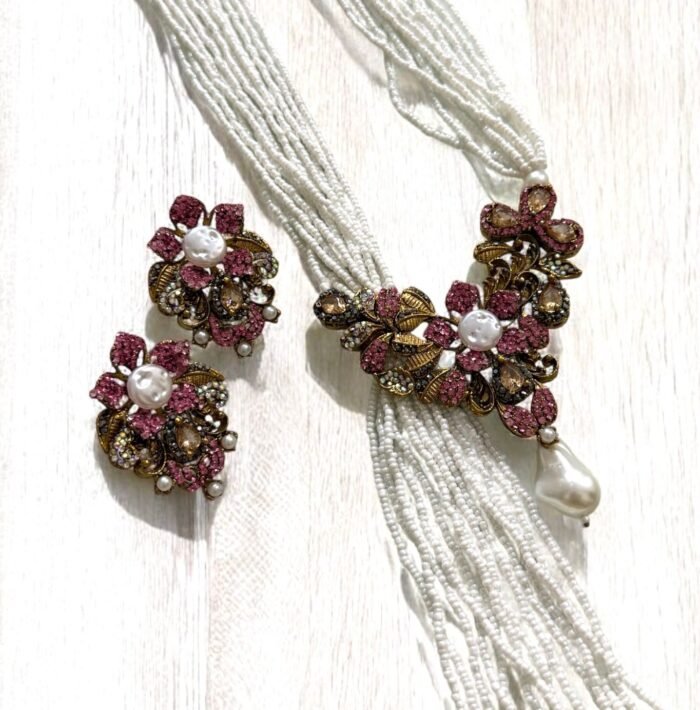 Gold-plated necklace with pink crystals, pearls, and floral accents, paired with matching earrings.