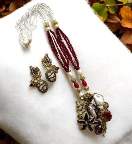 Gold-plated necklace with red beads, pearls, and gemstone embellishments, paired with matching earrings.