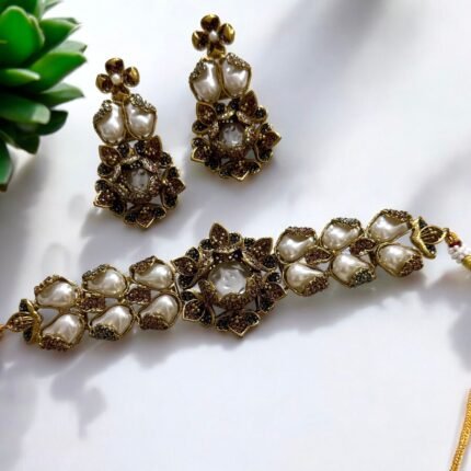 Gold necklace and earrings set with pearls and crystal embellishments in a floral design.
