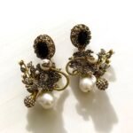 Gold earrings with peach gemstones, pearls, and crystal embellishments in a floral design.