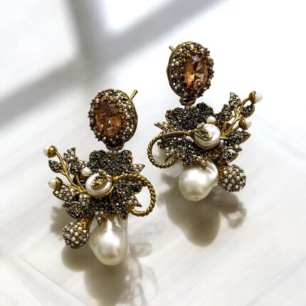 Gold earrings with peach gemstones, pearls, and crystal embellishments in a floral design.