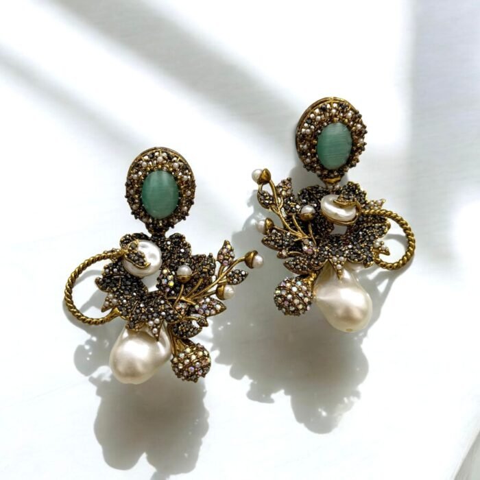 Gold earrings with peach gemstones, pearls, and crystal embellishments in a floral design.