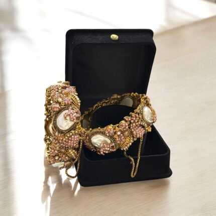Gold-plated bracelets with pink crystals and pearls in an ornate design.