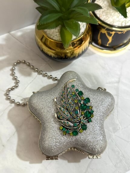 Silver star-shaped clutch with a green crystal leaf design and a detachable chain strap.