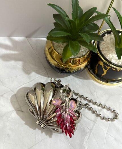 Silver clutch with a pink and red crystal peacock design, featuring a detachable chain strap.