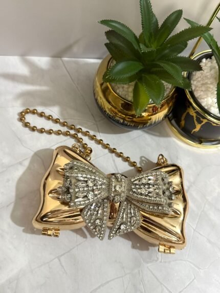 Gold bow-shaped clutch with crystal embellishments, featuring a detachable chain strap.