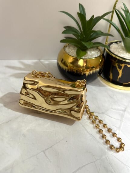 Gold clutch with a crystal turtle design, featuring a detachable gold chain strap.