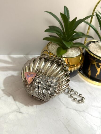 Silver clutch with a swan design, featuring crystal embellishments and a pink gemstone accent, with a detachable chain strap.