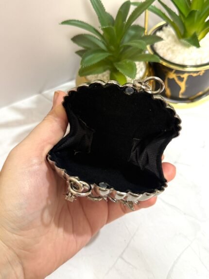 Silver clutch with a swan design, featuring crystal embellishments and a pink gemstone accent, with a detachable chain strap.