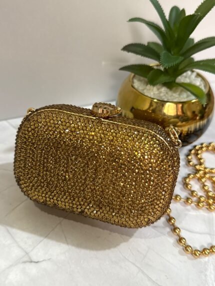 Gold clutch with crystal embellishments and a detachable gold chain strap.
