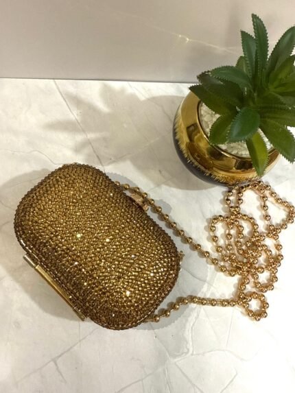Gold clutch with crystal embellishments and a detachable gold chain strap.