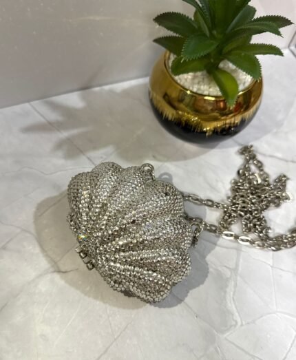 Silver crystal-embellished seashell-shaped clutch with a detachable silver chain strap.