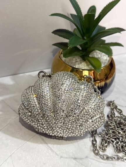 Silver crystal-embellished seashell-shaped clutch with a detachable silver chain strap.
