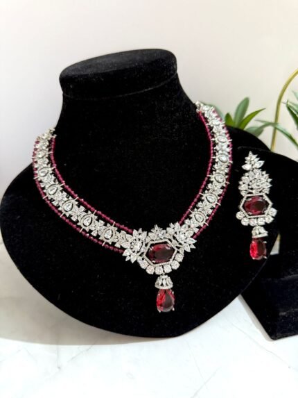 Red and diamond-style necklace with matching earrings, featuring a floral design and red teardrop gemstone accents.