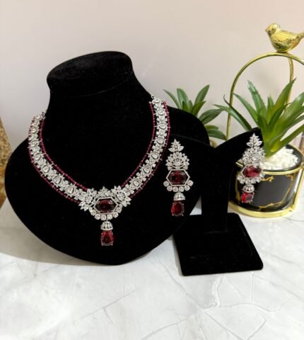 Red and diamond-style necklace with matching earrings, featuring a floral design and red teardrop gemstone accents.